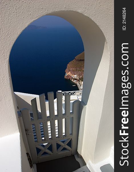 A doorway in Santorini (Thira), with a harbor in the distance. A doorway in Santorini (Thira), with a harbor in the distance.