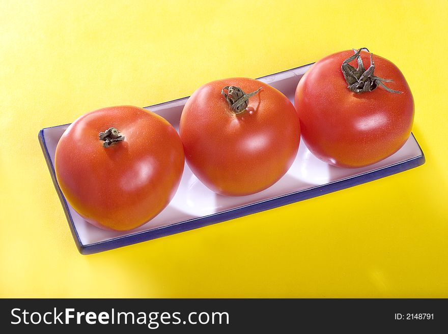 A photo of three tomatoes on the plate. A photo of three tomatoes on the plate