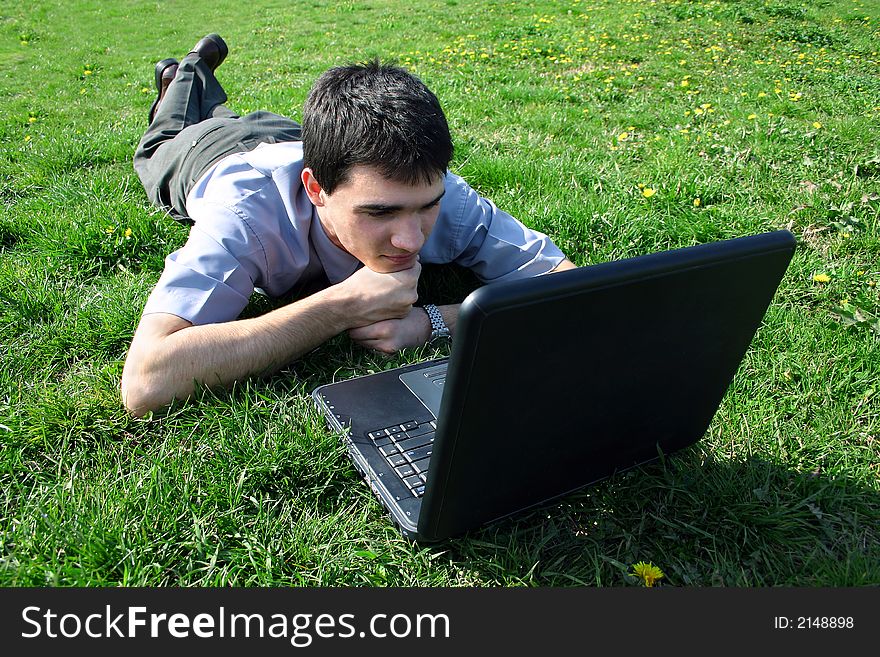 Young man relaxing,while watching something on his lap-top in nature,