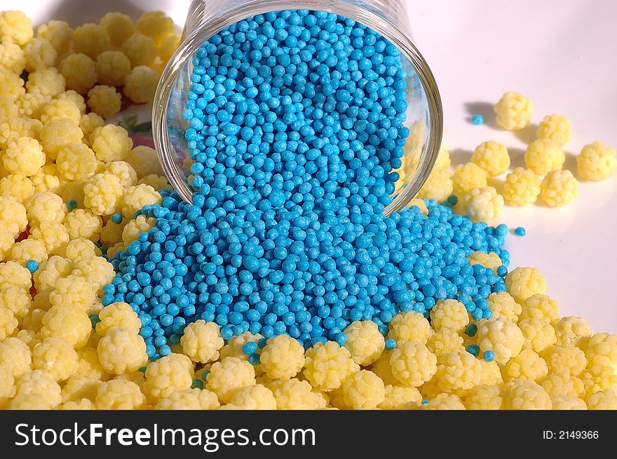 Small blue candies in a small glass on a saucer with yellow candies