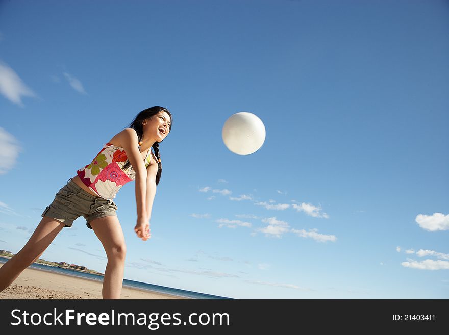 Teenage girl playing beach volleyball smiling