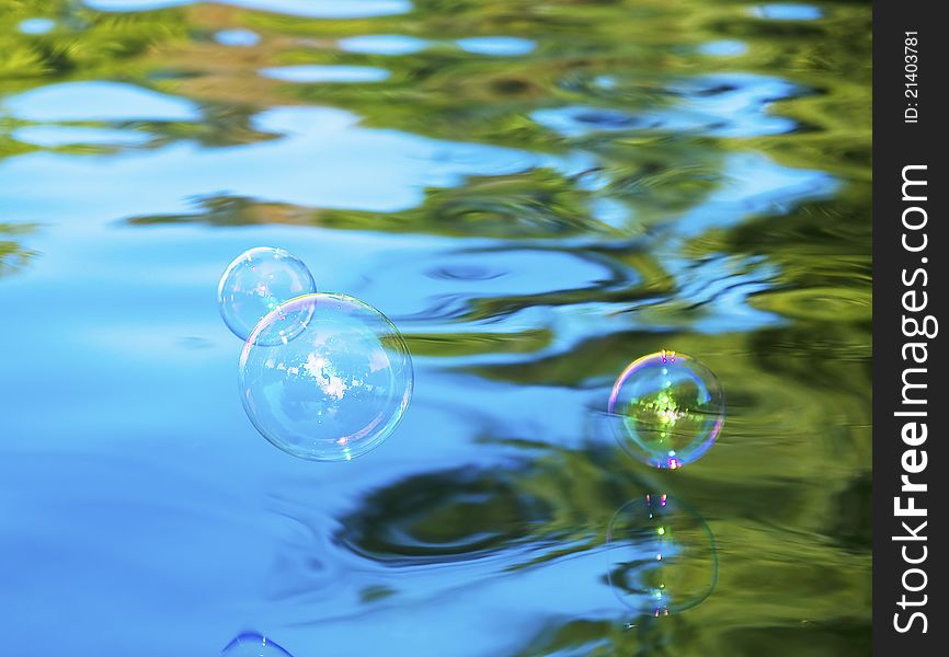 Soap bubbles flying above blue water. Soap bubbles flying above blue water.