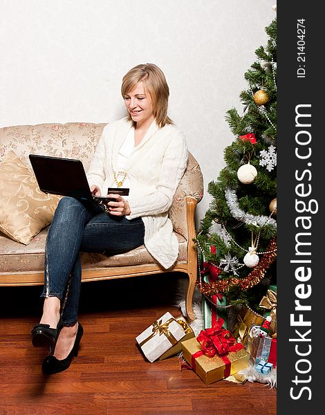 A young woman sits with a notebook near a new-year tree. A young woman sits with a notebook near a new-year tree