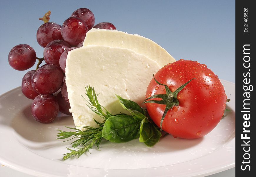 Mozarella cheese with tomato and grapes on white plate. Mozarella cheese with tomato and grapes on white plate