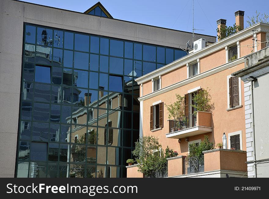 Flowers on balcony on a red building near a glass building. Flowers on balcony on a red building near a glass building