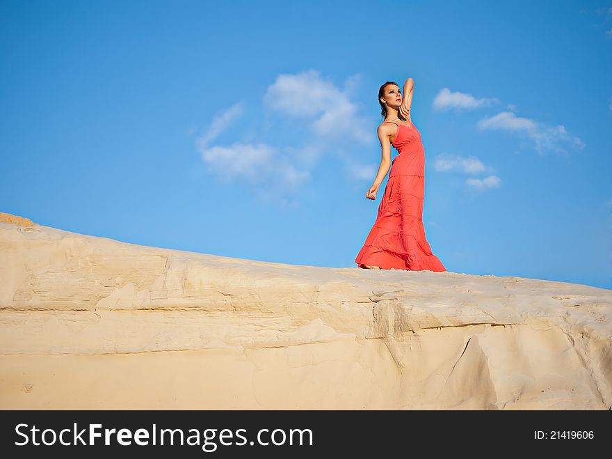 Portrait of a beauty woman in red dress on the desert
