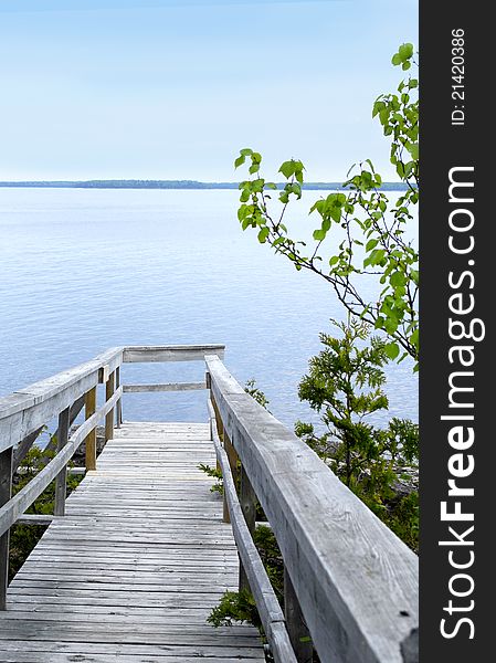 A wooden deck walkway leads to the edge of a the Georgian Bay, Ontario, Canada. A wooden deck walkway leads to the edge of a the Georgian Bay, Ontario, Canada