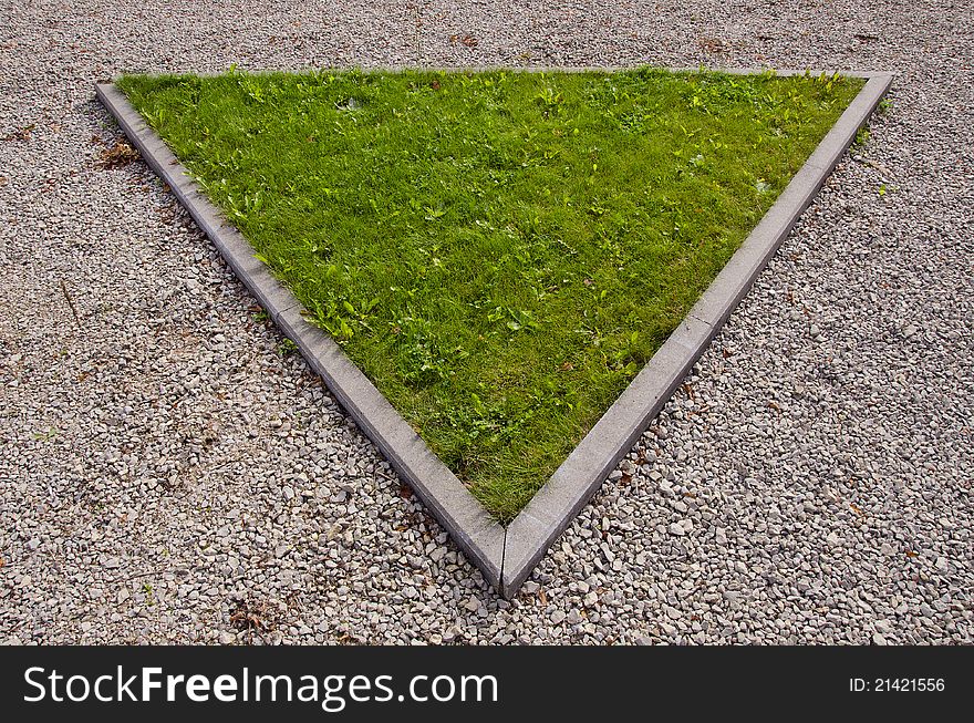 Green triangular island of grass surrounded by path in park. Green triangular island of grass surrounded by path in park.