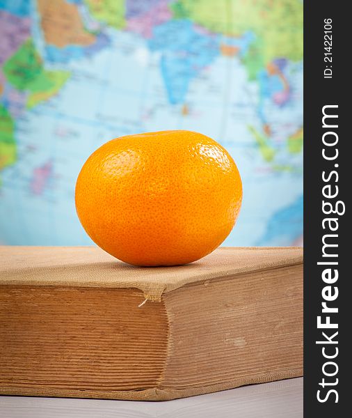 Orange on old book on globe background. Orange on old book on globe background