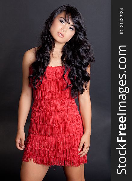 A portrait of a gorgeous young Asian woman in a red fringed flapper-style dress. A portrait of a gorgeous young Asian woman in a red fringed flapper-style dress