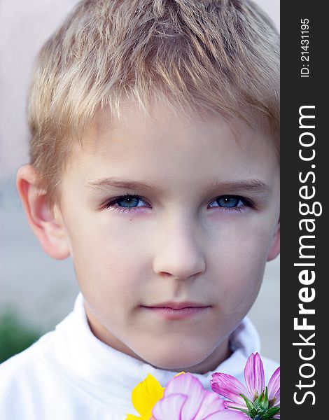 Portrait of the boy with a bouquet of flowers in hands.