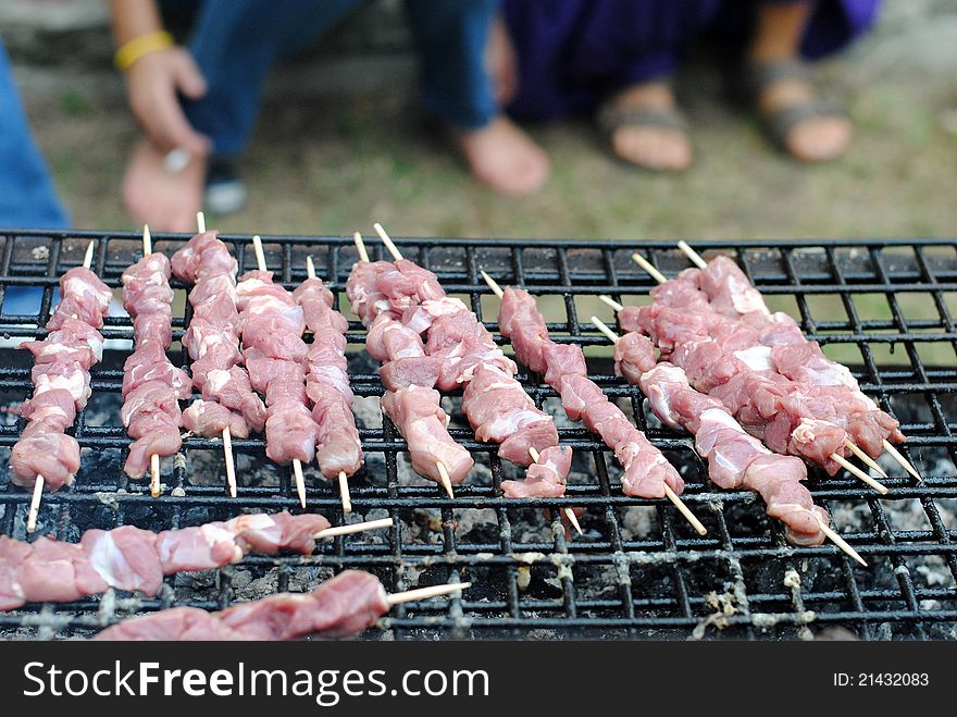 Lamb kabobs grilled on skewers, and people foot on background