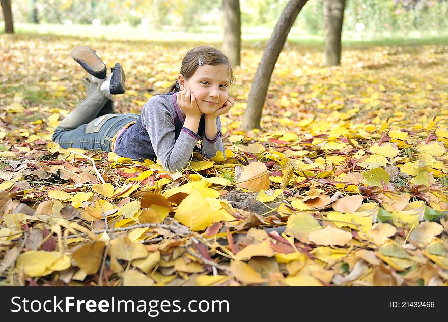 Girl Lying On Fall Leaves Outdoors