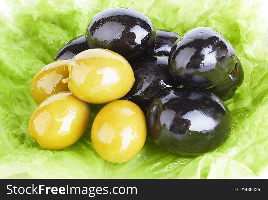 Black ripe olives in oil with a fresh green leaflet of salad