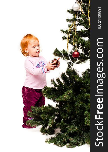 A little girl decorates a new-year tree on a white background