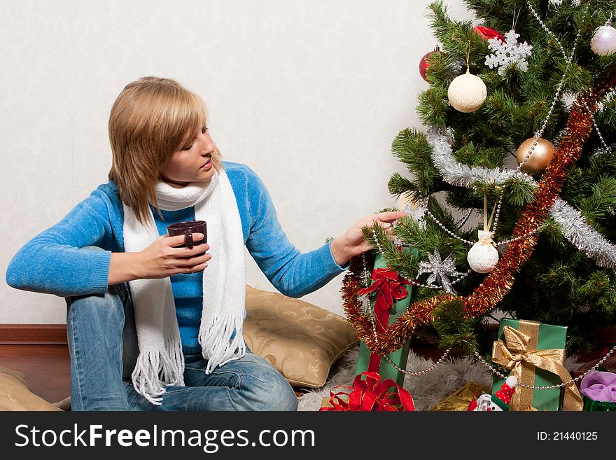 A young woman sits near a new-year tree. A young woman sits near a new-year tree