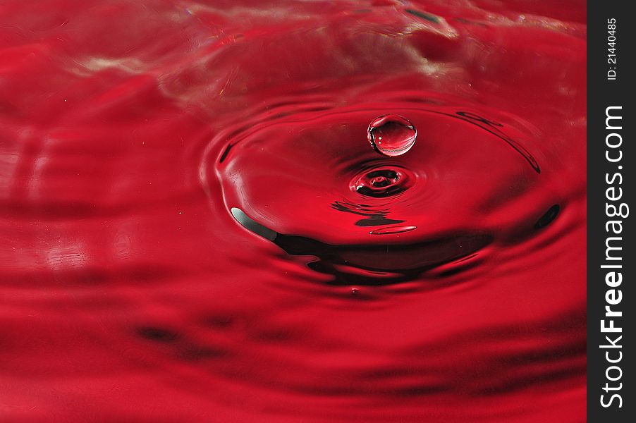 A water splash with drops in red color. A water splash with drops in red color.