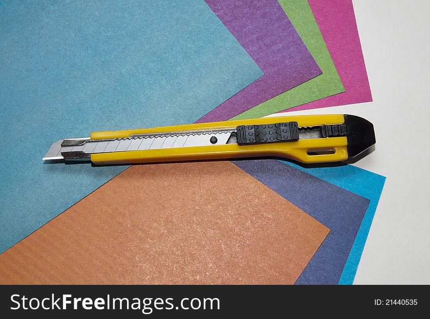 Knife for a paper on sheets of a color paper on grey background