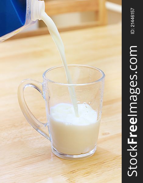 Pouring milk into a glass on wooden table