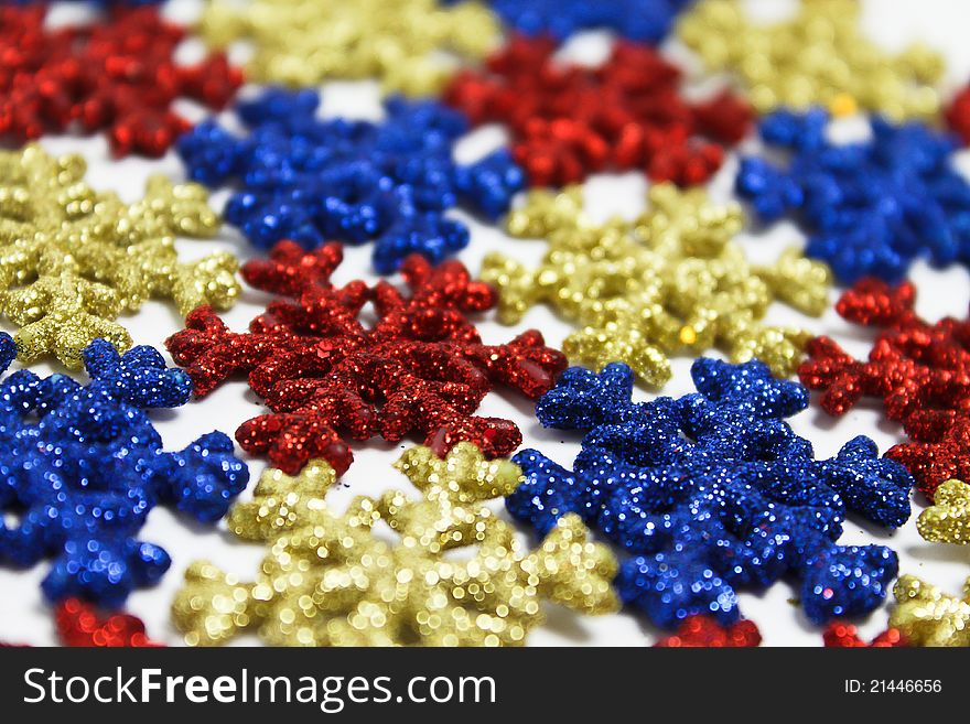 Red, blue and yellow plastic snowflakes on white. Red, blue and yellow plastic snowflakes on white