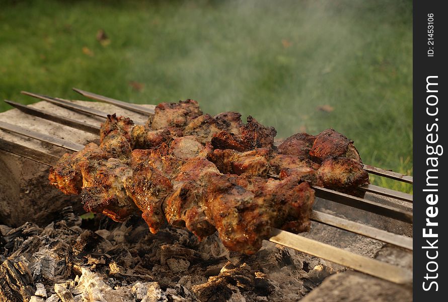 Smoke and barbecue of meat on skewers over a hot charcoal. Smoke and barbecue of meat on skewers over a hot charcoal