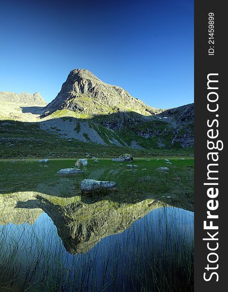 Tall mountain peak reflected in a natural lake, Troms County, northern Norway. Tall mountain peak reflected in a natural lake, Troms County, northern Norway