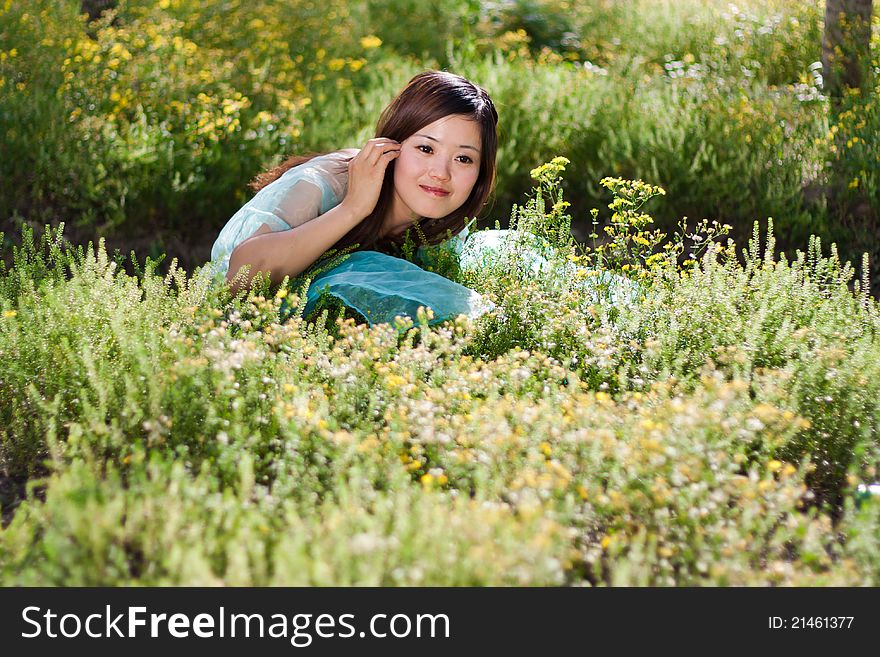 Young beautiful girl laying on the flowers field, outdoor portrait, China