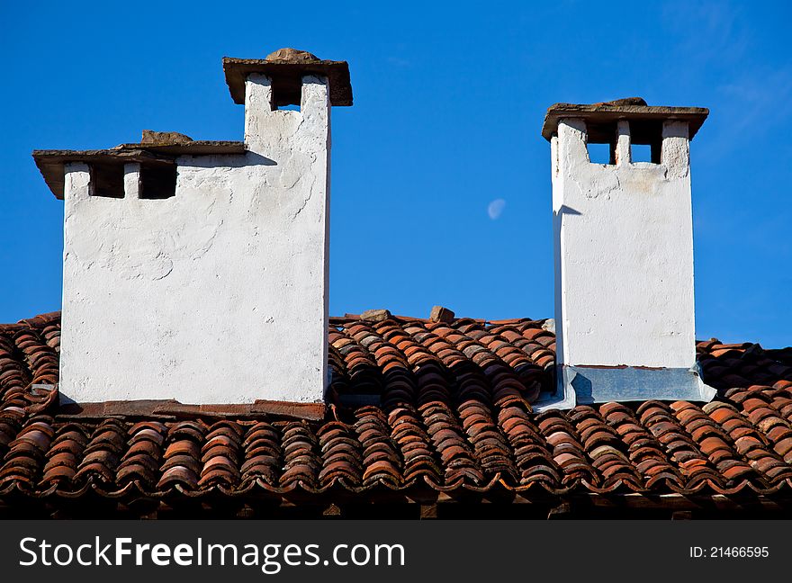 Tiled house roof with two stone chimneys. Tiled house roof with two stone chimneys
