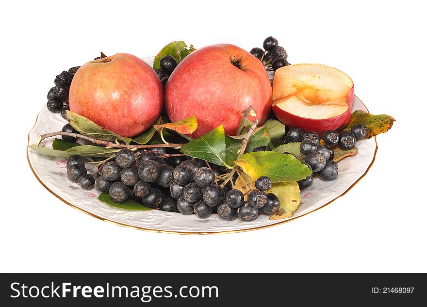 The black mountain ash and apples lie on a plate. The black mountain ash and apples lie on a plate