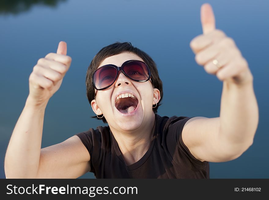 Young brunette girl with big funny sunglasses making thumbs up gesture - shallow depth of field. Young brunette girl with big funny sunglasses making thumbs up gesture - shallow depth of field