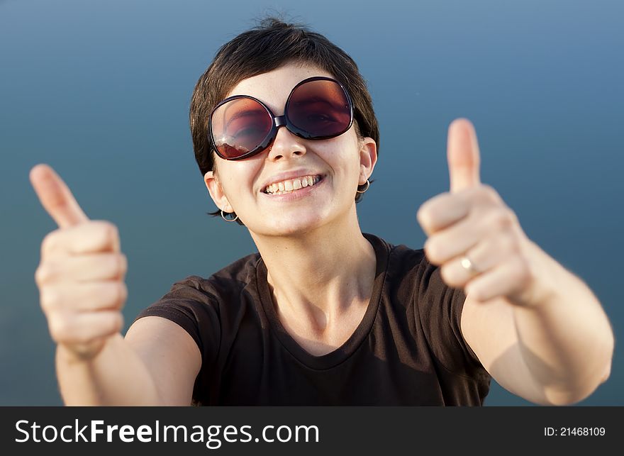 Young brunette girl with big funny sunglasses making thumbs up gesture - shallow depth of field. Young brunette girl with big funny sunglasses making thumbs up gesture - shallow depth of field