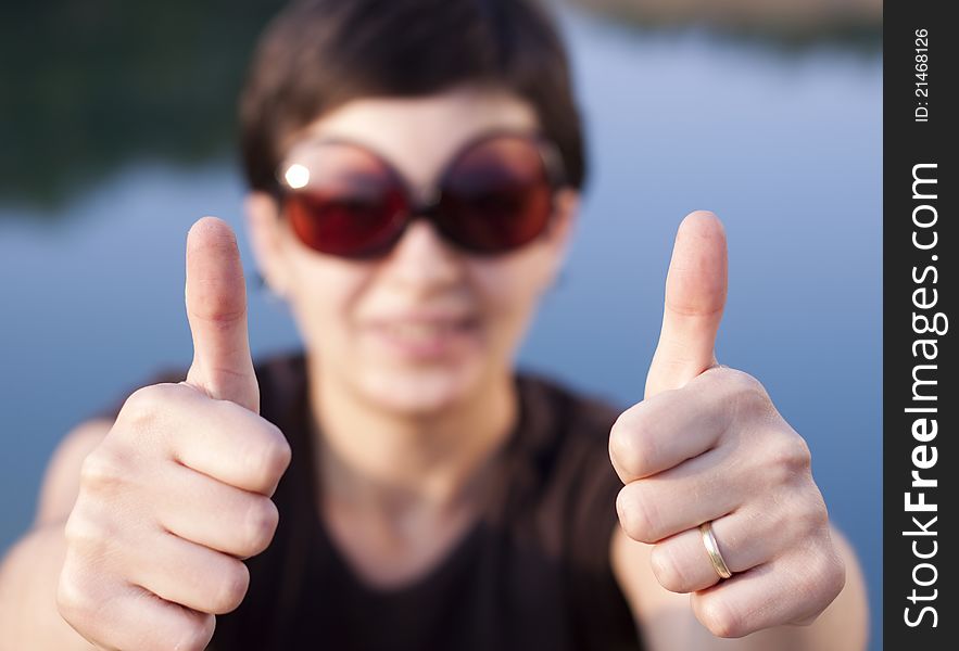 Young brunette girl with big funny sunglasses making thumbs up gesture - shallow depth of field. Young brunette girl with big funny sunglasses making thumbs up gesture - shallow depth of field