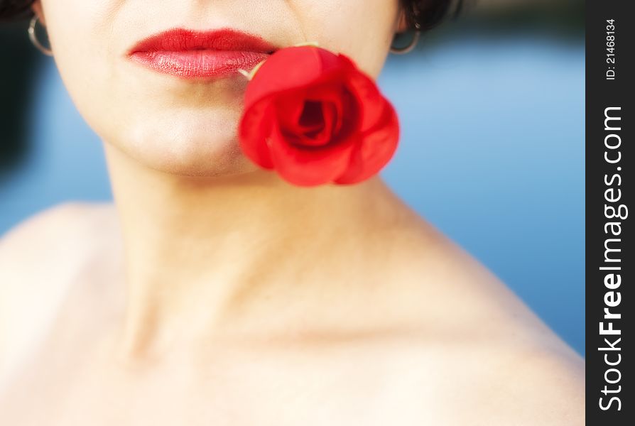 Woman with red lips holding red rose in mouth. Woman with red lips holding red rose in mouth