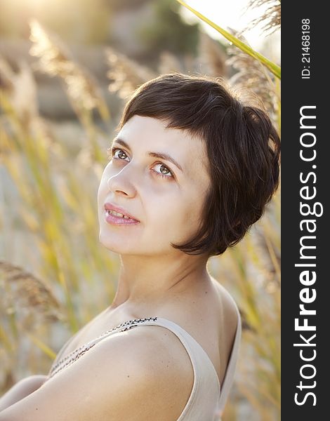 Portrait of beautiful brunette woman in summer reed