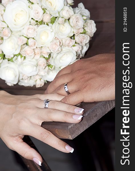 Hands and rings on wedding bouquet