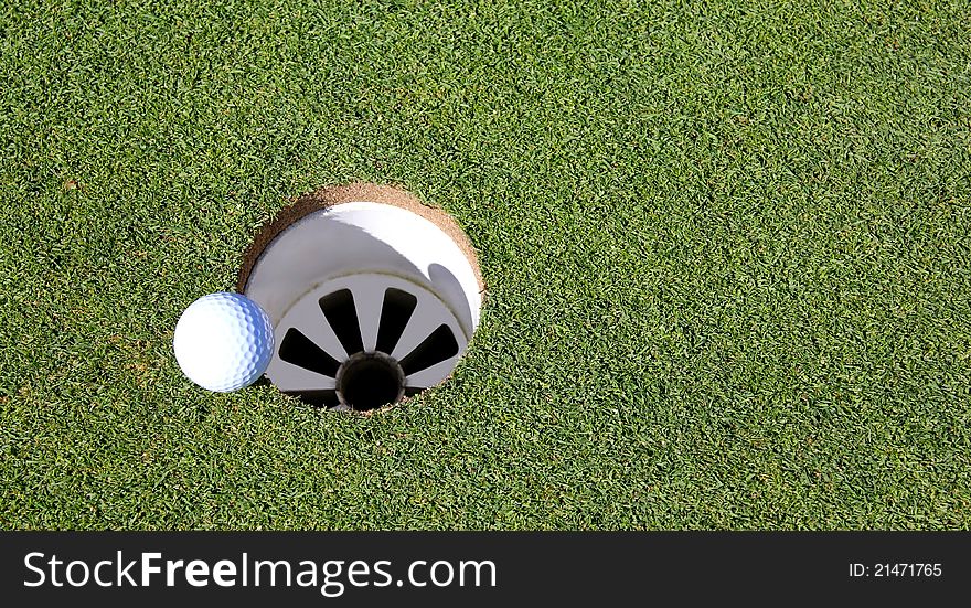 Golf ball on the edge of the hole , close to dropping in