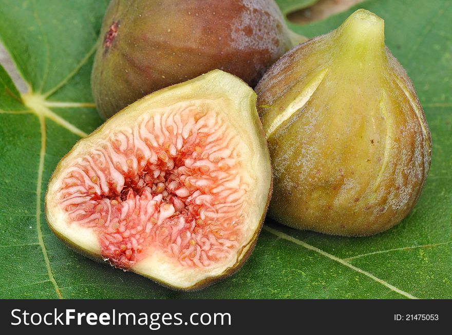 Half of figs and fig whole resting on a fig leaf