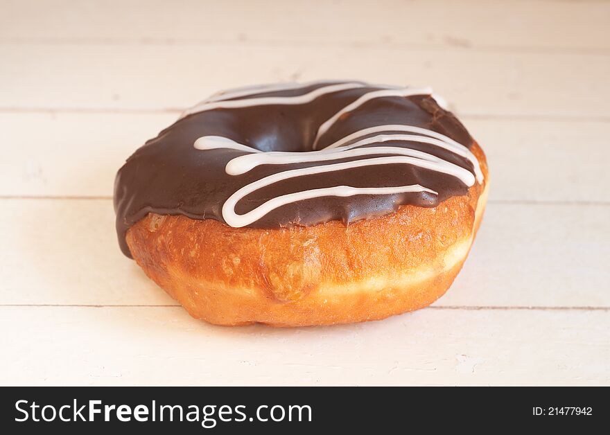 Donut covered in chocolate icing on grunge wooden background. Donut covered in chocolate icing on grunge wooden background