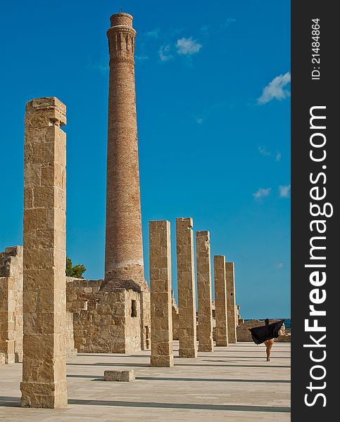 Walking woman on tuna fishing ruins natural oasis during sunset, there is an brick smokestack and pillars. Walking woman on tuna fishing ruins natural oasis during sunset, there is an brick smokestack and pillars.