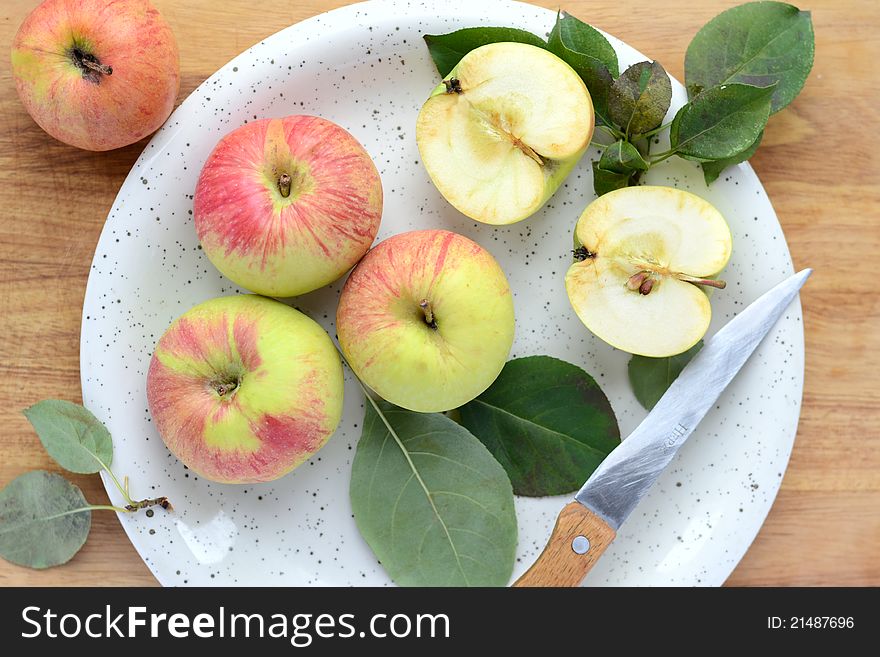 Apples, leaves and knife on plate