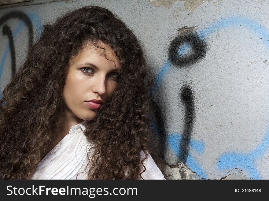 Woman with curly hair holding a protective cap in hand and looks into the camera