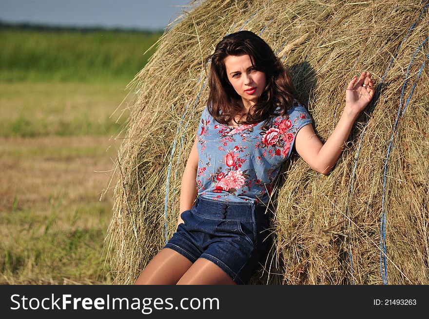 Young beautiful woman is standing near a straw. Young beautiful woman is standing near a straw