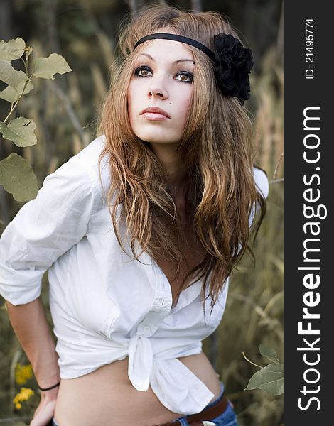 Young beautiful woman with brown eyes stands in a pale grass. Young beautiful woman with brown eyes stands in a pale grass.