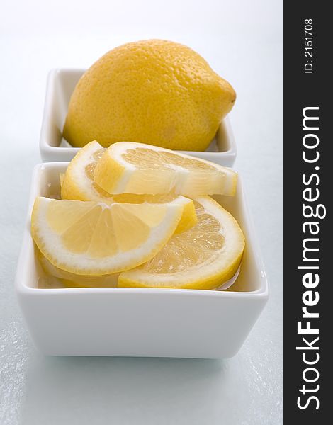 Bar garnish of fresh sliced lemon for any cocktail. Sliced Lemons place in a square bowl with water. Bar garnish of fresh sliced lemon for any cocktail. Sliced Lemons place in a square bowl with water.