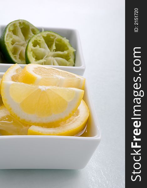 Bar garnish of fresh sliced lemon  and squeezed lime for any cocktail. Sliced Lemons and limes placed in a square bowl with water. Bar garnish of fresh sliced lemon  and squeezed lime for any cocktail. Sliced Lemons and limes placed in a square bowl with water.