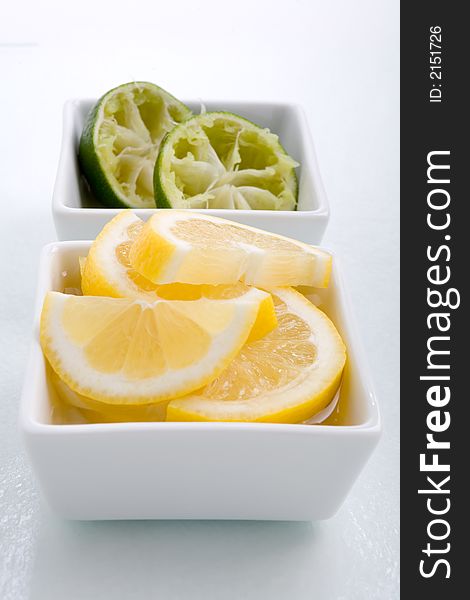 Bar garnish of fresh sliced lemon  and squeezed lime for any cocktail. Sliced Lemons and limes placed in a square bowl with water. Bar garnish of fresh sliced lemon  and squeezed lime for any cocktail. Sliced Lemons and limes placed in a square bowl with water.