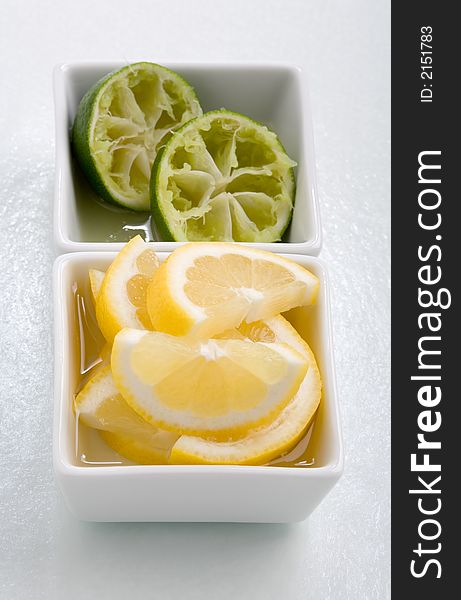 Bar garnish of fresh sliced lemon  and squeezed lime for any cocktail. Sliced Lemons and limes placed in a square bowl with water. Bar garnish of fresh sliced lemon  and squeezed lime for any cocktail. Sliced Lemons and limes placed in a square bowl with water.