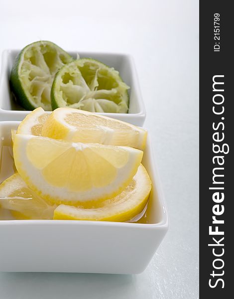 Bar garnish of fresh sliced lemon  and squeezed lime for any cocktail. Sliced Lemons and limes placed in a square bowl with water. Bar garnish of fresh sliced lemon  and squeezed lime for any cocktail. Sliced Lemons and limes placed in a square bowl with water.