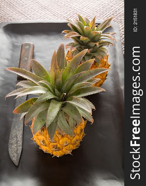 Two Mini Pineapples with a old knife on a wooden board