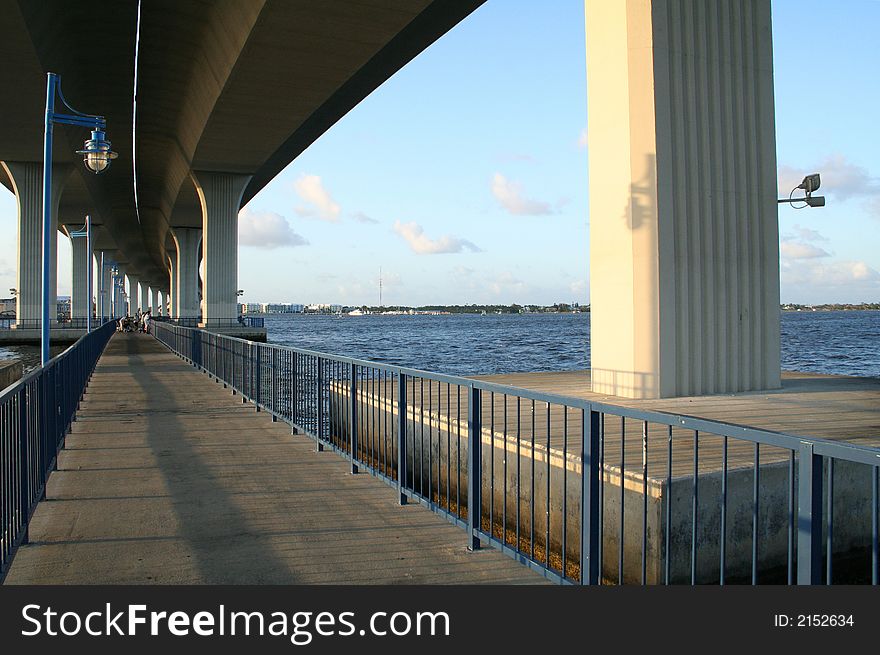 Tall Bridge over Fishing Recreation Area. River scenic with blue sky and clouds. Horizon visible. Tall Bridge over Fishing Recreation Area. River scenic with blue sky and clouds. Horizon visible.